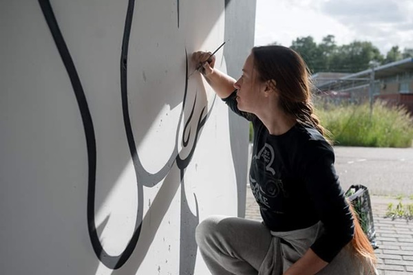 Frau gestaltet ein Wandgemälde an der Halle des Ruhmes (Hall of Fame) in Weert